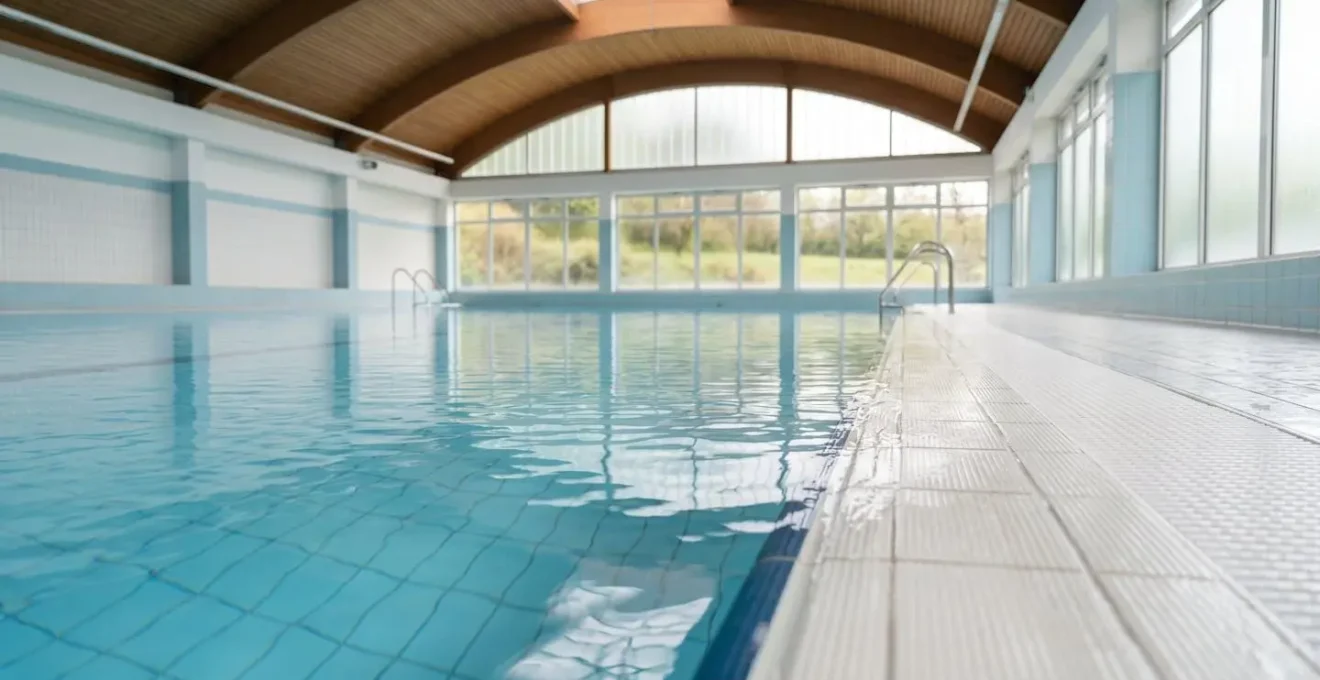 Vue large et minimaliste d'un bassin de piscine calme avec des reflets de lumière naturelle sur l'eau et un espace négatif apaisant