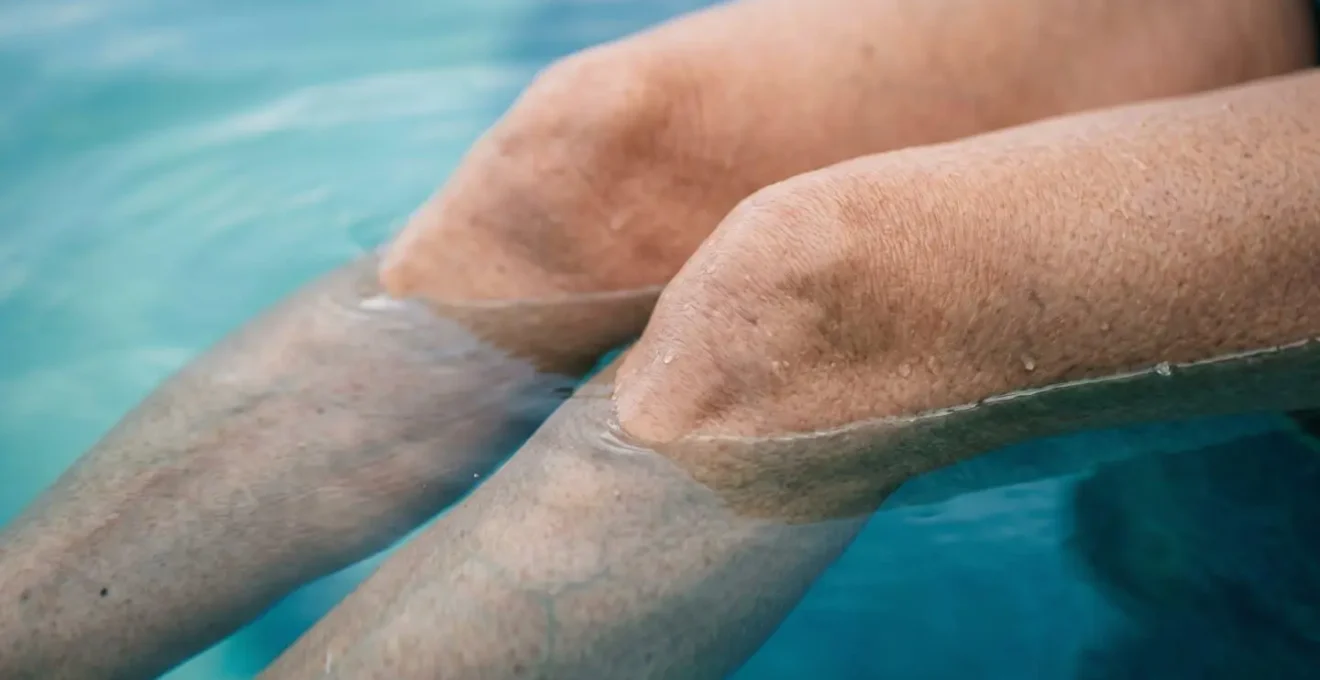 Gros plan sur des jambes de senior immergées dans l'eau, illustrant la sensation d'apesanteur et le soulagement articulaire